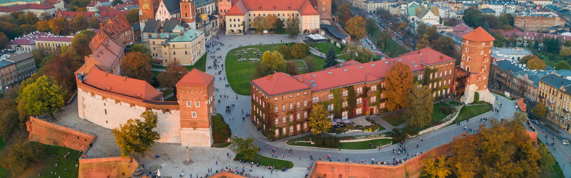 Wawel Royal Castle in Krakow. Aerial view of the castle courtyard and the walls surrounding the castle. There is a view of the city around a tree in the distance.