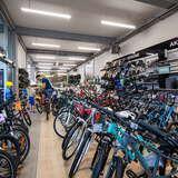 Dziesiątki rowerów ustawionych w rzędzie, na półkach akcesoria rowerowe